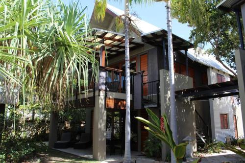 a house with a balcony and palm trees at Pure Magnetic Villa 8 in Nelly Bay
