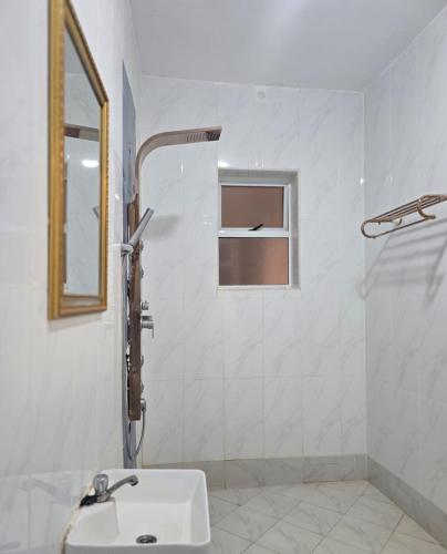 a white bathroom with a sink and a shower at Lesha Park Hotel in Libwezi