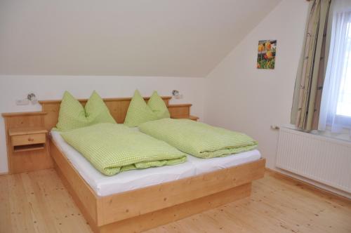 a bedroom with a bed with green pillows on it at Ferienhof Berger in Rossleithen