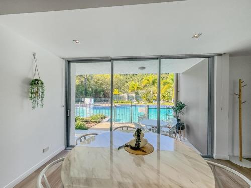 a dining room with a table and a large window at Blue on Blue Apartment 1011 in Nelly Bay