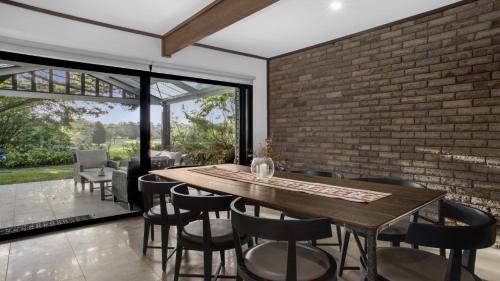 a dining room with a brick wall and a wooden table and chairs at The Castle Wentworth Falls in Wentworth Falls