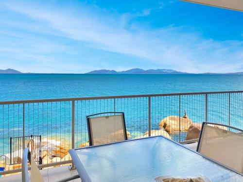 a balcony with a table and chairs and the ocean at 1 Bright Point Apartment 4203 in Nelly Bay