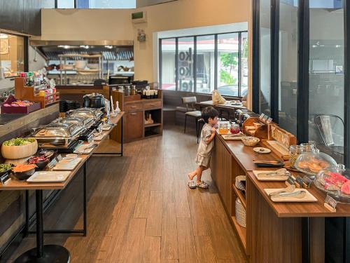 a little boy standing at the counter of a restaurant at Kokotel Bangkok Surawong in Bangkok