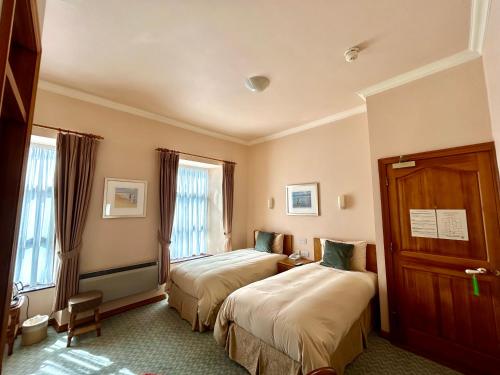 a hotel room with two beds and two windows at Rathbaun Hotel in Lisdoonvarna