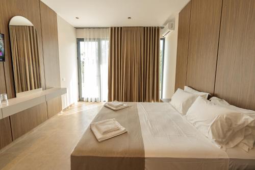 a bedroom with a large bed and a large window at Abeille Rooms in Himare