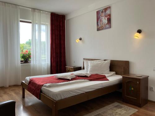 a bedroom with a bed with a red blanket and a window at Pensiunea Cetatea Craiului in Râşnov