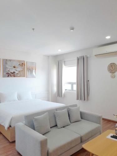 a white bedroom with a bed and a couch at Juna hotel - Condotel in Thanh Hóa