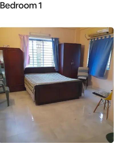 a bedroom with a bed and a window with blue curtains at Sir Residency in Howrah