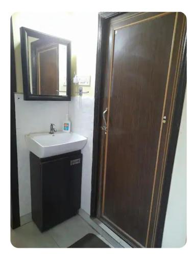 a bathroom with a sink and a wooden door at Sir Residency in Howrah