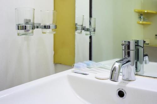 a bathroom sink with a faucet and a mirror at Amaris Hotel Padang in Padang