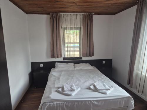 a bedroom with a bed with white sheets and a window at Къща Цачеви 2 in Tryavna
