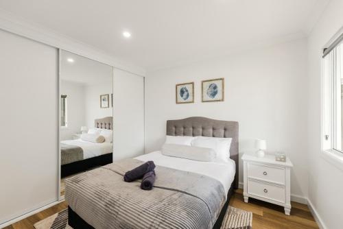 a white bedroom with two beds and a mirror at Ralph Escapes Kingsley in Perth