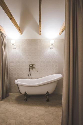 a white bath tub in a bathroom with two lights at Sodyba Pelėdų medus in Vainekoniai