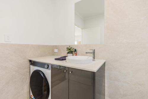 a bathroom with a washing machine and a sink at Ralph Escapes Kingsley in Perth