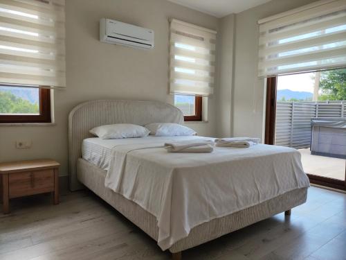 ein Schlafzimmer mit einem Bett mit weißen Laken und Fenstern in der Unterkunft Pronaos in Ortaca
