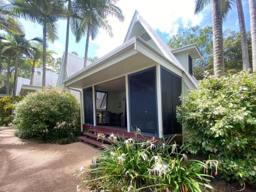 a small house with a large window and palm trees at Canopy Chalet 4 in Nelly Bay
