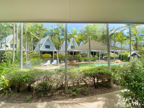 a view of a house with a pool and palm trees at Canopy Chalet 4 in Nelly Bay