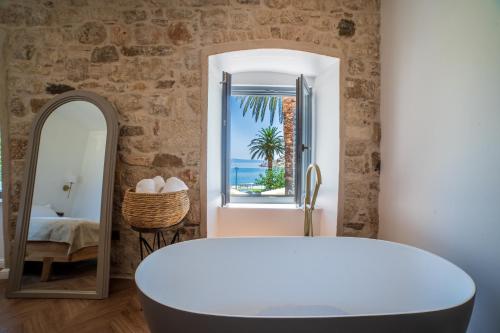 a bathroom with a white tub and a mirror at Hotel Heritage Casa Blanka in Makarska