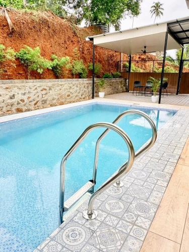 a swimming pool with a metal handrail next to at Ginger Villa Farmstay, Thodupuzha in Idukki