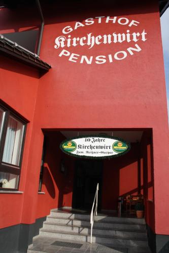 a red building with a sign for a restaurant at Pension Kirchenwirt in Niederaichbach