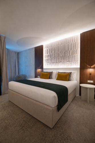 a bedroom with a large white bed with yellow pillows at Hotel Palladia in Toulouse