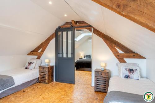a attic bedroom with two beds and two tables at Le gite des ecuries de marquecy in Évricourt
