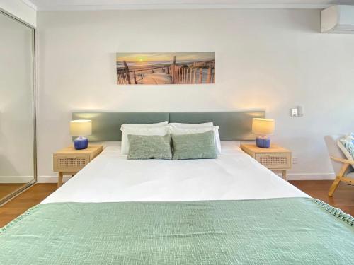 a bedroom with a large white bed with two lamps at Blue on Blue Studio Room 1222 in Nelly Bay