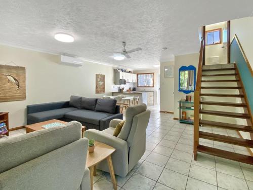 a living room with a couch and a staircase at Island Magic Townhouse 5 in Arcadia