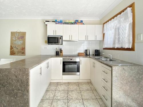 a kitchen with white cabinets and a sink and a microwave at Island Magic Townhouse 5 in Arcadia
