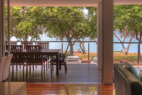 a dining table and chairs on a deck with a view of the water at Maggies Beachfront Apartment 10 in Horseshoe Bay