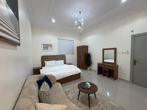 a bedroom with a bed and a couch and a table at شادن للوحدات السكنية in Qufār