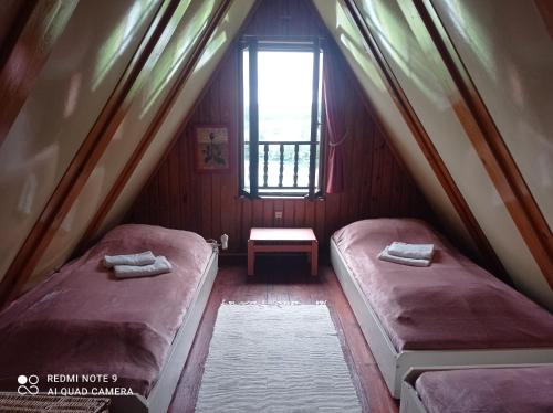 two beds in a small room with a window at domek Kaszuby nad jeziorem in Chmielno