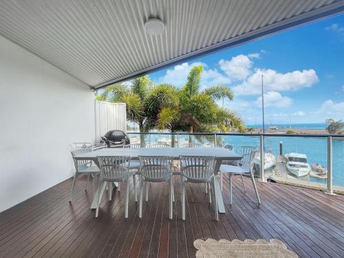 a table and chairs on a deck with a view of the ocean at Waters Edge Townhouse 4 in Nelly Bay