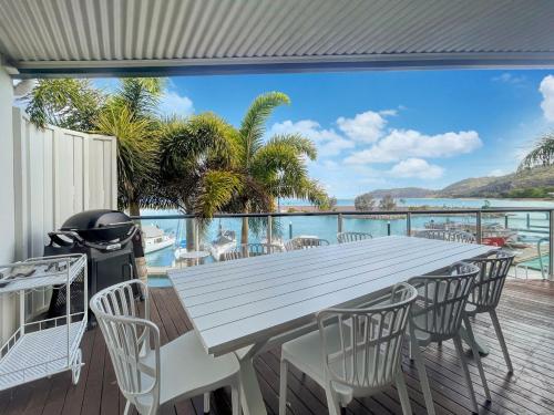 a white table and chairs on a deck with a view of the ocean at Waters Edge Townhouse 4 in Nelly Bay
