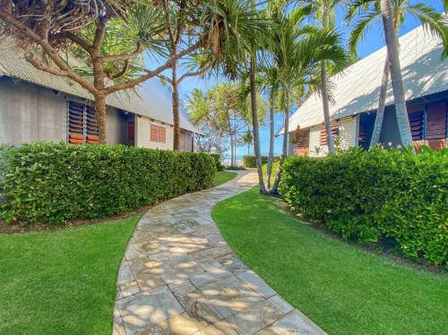 a stone walkway next to a house with palm trees at Pure Magnetic Villa 4 in Nelly Bay