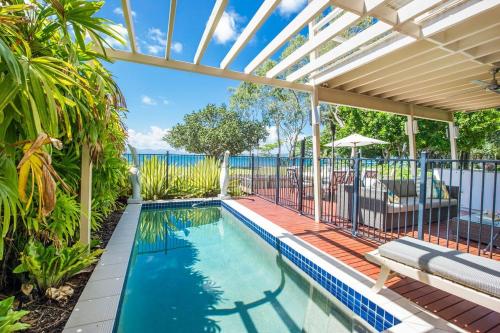 an outdoor swimming pool with a pergola and a swimming poolvisor at Eeast on Picnic in Picnic Bay