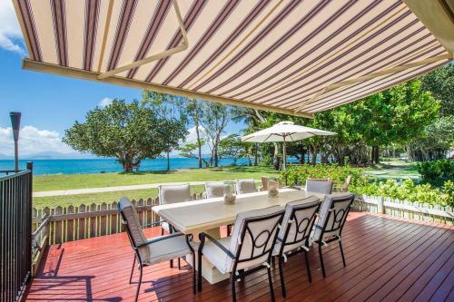 a wooden deck with a table and chairs and an umbrella at Eeast on Picnic in Picnic Bay