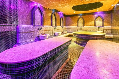 ein Badezimmer mit rosa Beleuchtung, Waschbecken und Toiletten in der Unterkunft Terra Hotel in Bansko