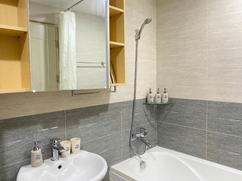 a bathroom with a sink and a mirror and a tub at Juna hotel - Condotel in Thanh Hóa