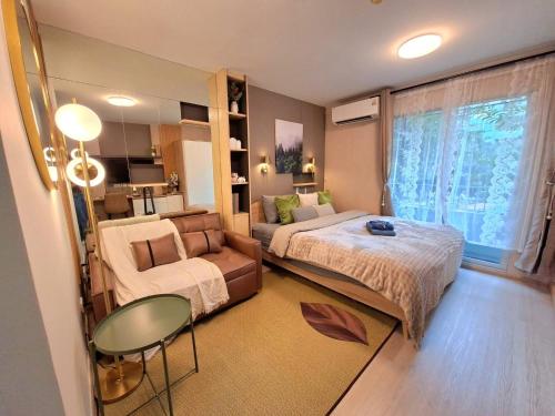 a bedroom with a bed and a couch and a table at Modern Studio Pool View, King bed, BTS Punnawithi in Bangkok