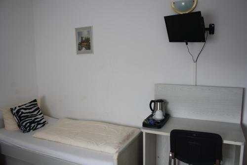 a room with a bed and a desk with a tv at Pension Kirchenwirt in Niederaichbach