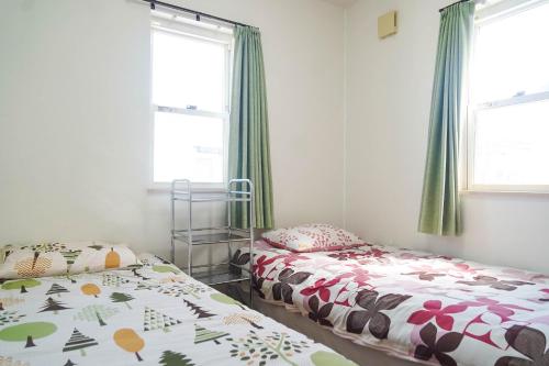 a bedroom with two beds and two windows at Katsuragawa House in Kami-tobachō