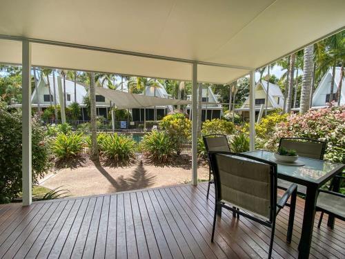 a patio with a table and chairs on a deck at Canopy Chalet 10 in Nelly Bay