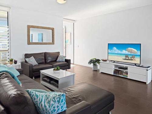 a living room with a couch and a flat screen tv at 1 Bright Point Apartment 4501 in Nelly Bay