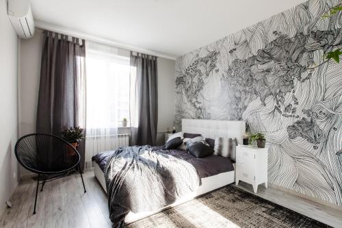 ワルシャワにあるApartament Plac Zbawicielaのベッドルーム1室(ベッド1台付)が備わります。壁に壁画が飾られています。