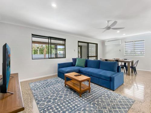 a living room with a blue couch and a table at Nerita Nook in Nelly Bay
