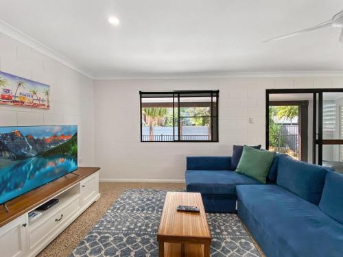 a living room with a blue couch and a flat screen tv at Nerita Nook in Nelly Bay