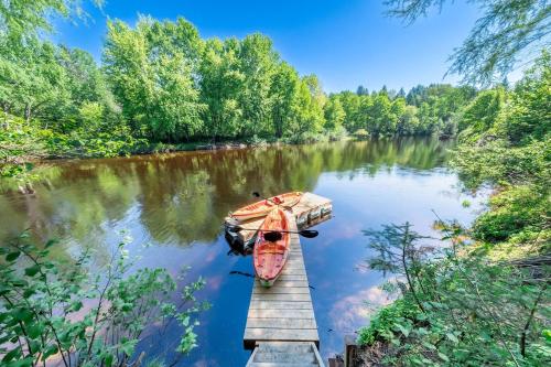 a boat is parked next to a dock on a river at Pool Table et Nature - Chalet de la riviere in Saint-Alexis-des-Monts