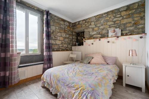 a bedroom with a bed and a stone wall at Appartement centre de Crozon in Crozon