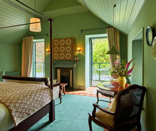 a bedroom with a bed and a table and a fireplace at Penmaenuchaf Hotel in Dolgellau